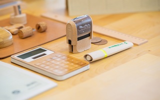 Taschenrechner, Stempel und Edding auf Schreibtisch